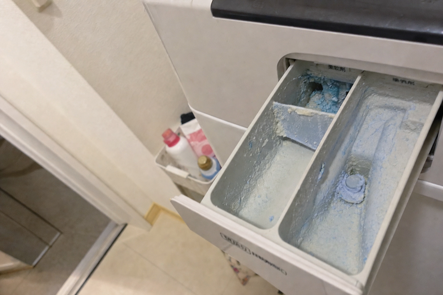 洗濯機の洗剤投入口に固まった洗剤カスや柔軟剤が残っている様子